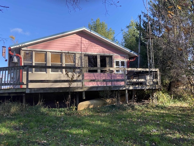 back of property with a deck and a lawn