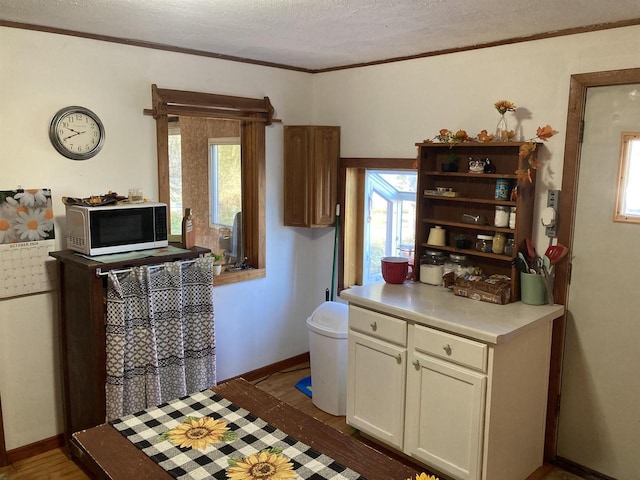 kitchen with ornamental molding, a textured ceiling, and dark hardwood / wood-style flooring