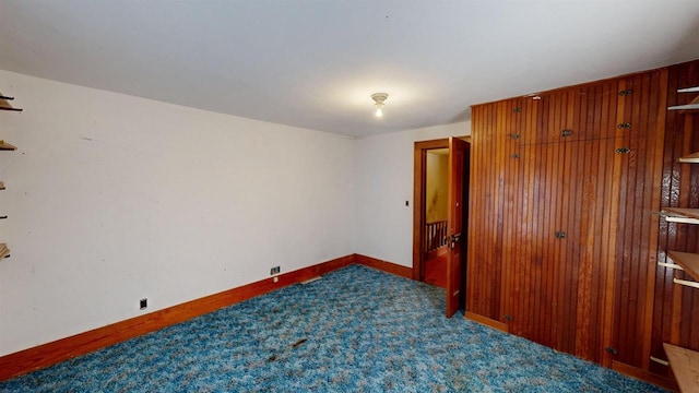 carpeted spare room with wood walls