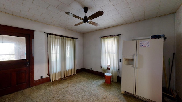 foyer entrance with ceiling fan, carpet floors, and plenty of natural light