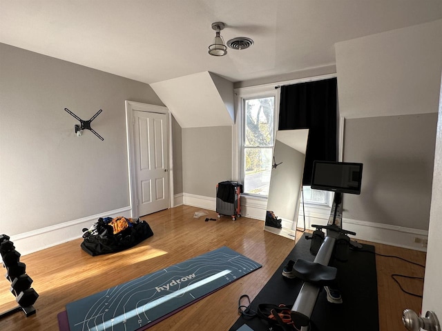 workout area featuring dark wood-type flooring and vaulted ceiling