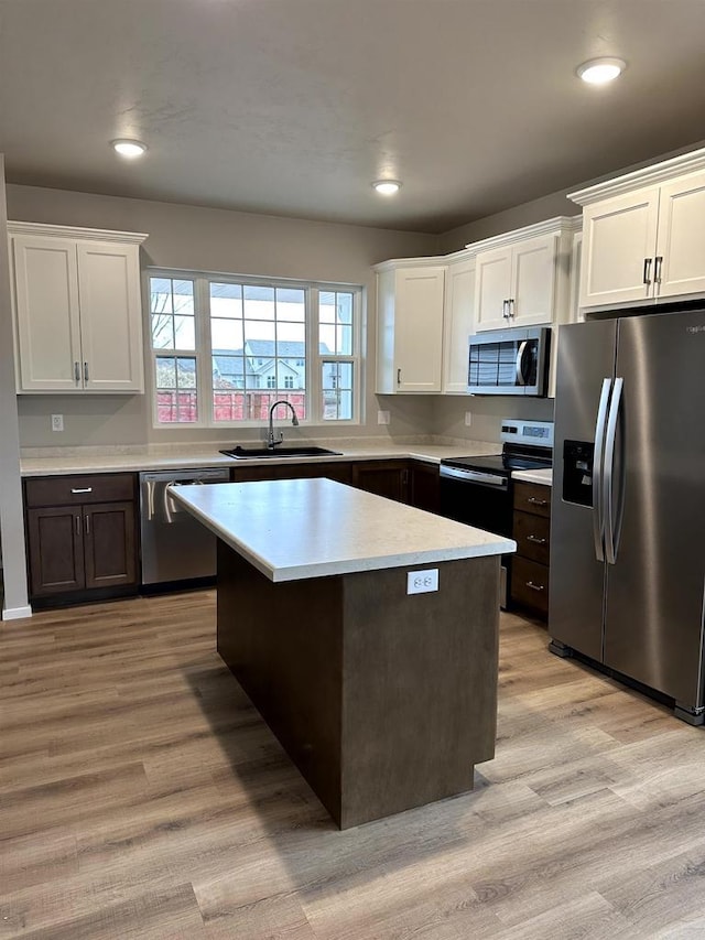 kitchen with white cabinetry, sink, light hardwood / wood-style flooring, dark brown cabinets, and appliances with stainless steel finishes