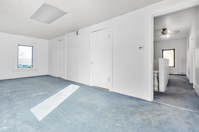 carpeted spare room with ceiling fan and plenty of natural light