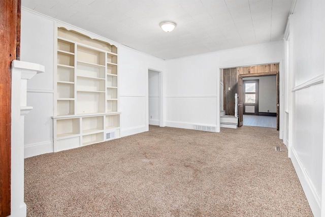 unfurnished living room featuring crown molding and carpet floors