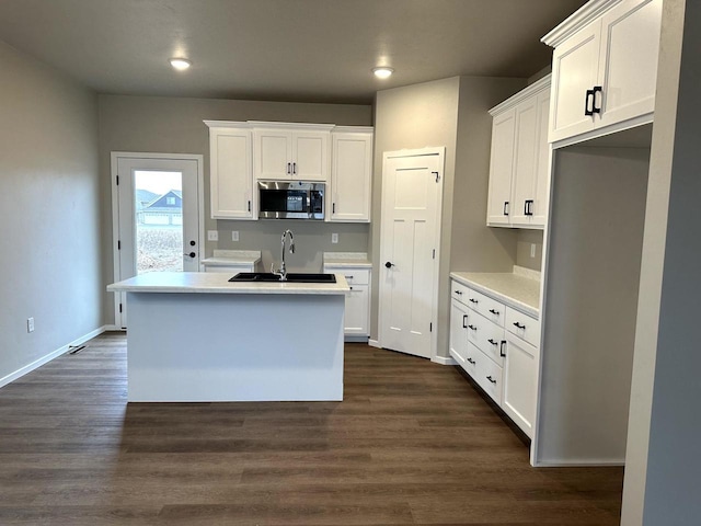 kitchen featuring white cabinetry, sink, dark wood-type flooring, and an island with sink