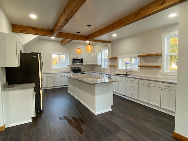 kitchen featuring hanging light fixtures, backsplash, appliances with stainless steel finishes, an island with sink, and dark wood-type flooring