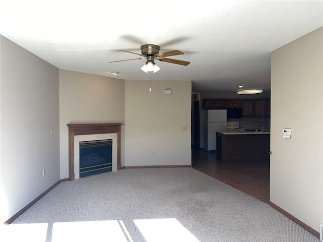 unfurnished living room with dark wood-type flooring, ceiling fan, and sink