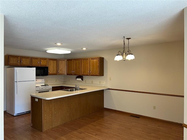 kitchen featuring kitchen peninsula, dark hardwood / wood-style flooring, an inviting chandelier, pendant lighting, and white appliances