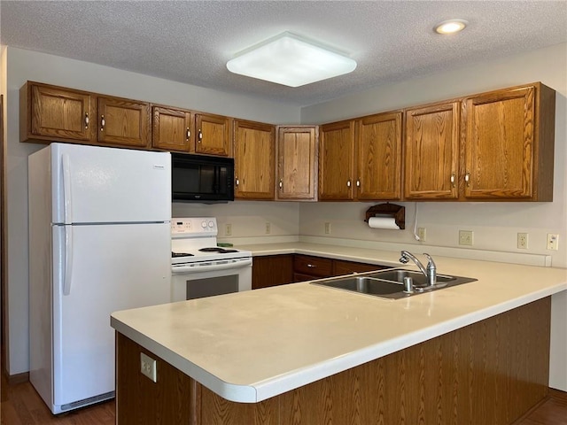 kitchen with kitchen peninsula, a textured ceiling, dark wood-type flooring, sink, and white appliances