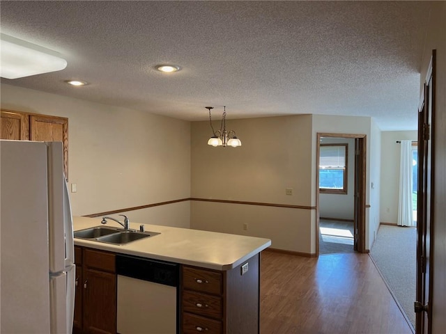 kitchen featuring light hardwood / wood-style floors, a textured ceiling, decorative light fixtures, and white appliances