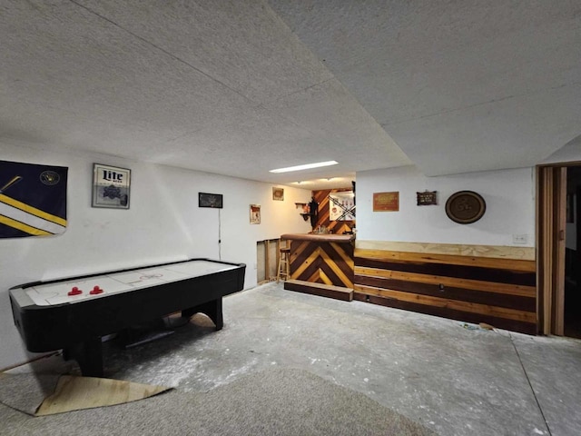 playroom with a dry bar, concrete floors, and a textured ceiling