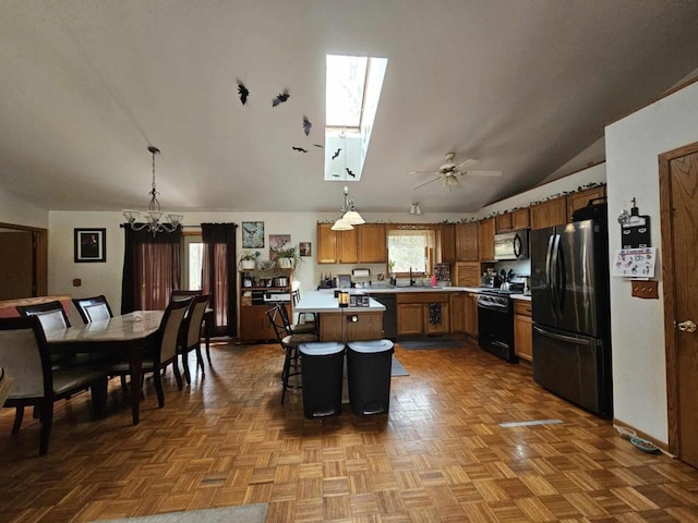 kitchen with a breakfast bar area, black appliances, lofted ceiling with skylight, decorative light fixtures, and a center island