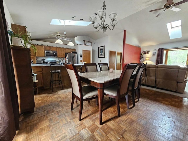 dining area featuring vaulted ceiling with skylight and ceiling fan with notable chandelier