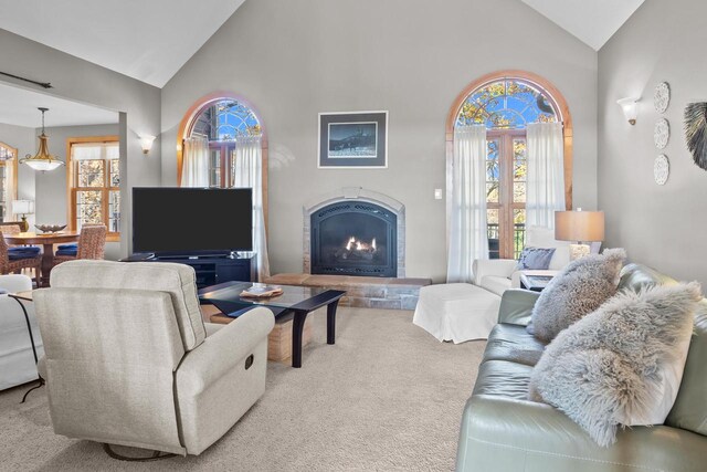 carpeted living room with high vaulted ceiling and a wealth of natural light