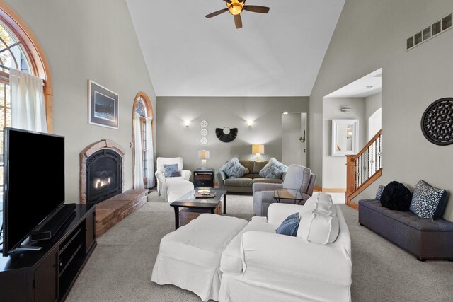 carpeted living room featuring ceiling fan, high vaulted ceiling, and a fireplace