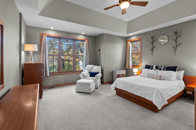 bedroom featuring a raised ceiling, carpet flooring, and ceiling fan