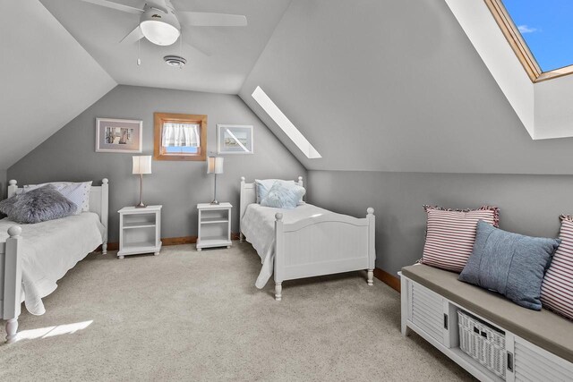 bedroom with ceiling fan, light carpet, and vaulted ceiling with skylight