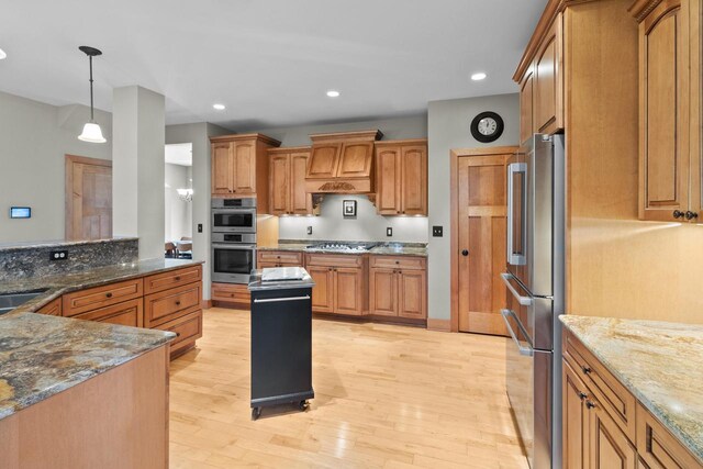 kitchen featuring custom range hood, stainless steel appliances, light wood-type flooring, and dark stone countertops