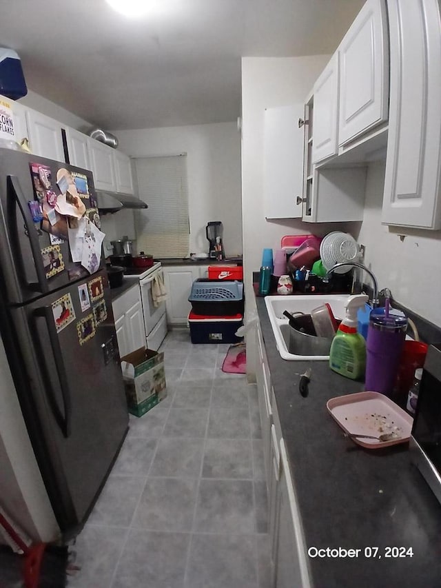 kitchen featuring sink, stainless steel fridge, white range with electric cooktop, light tile patterned floors, and white cabinetry