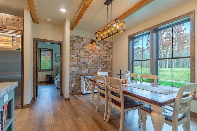 dining area featuring light hardwood / wood-style floors and beamed ceiling