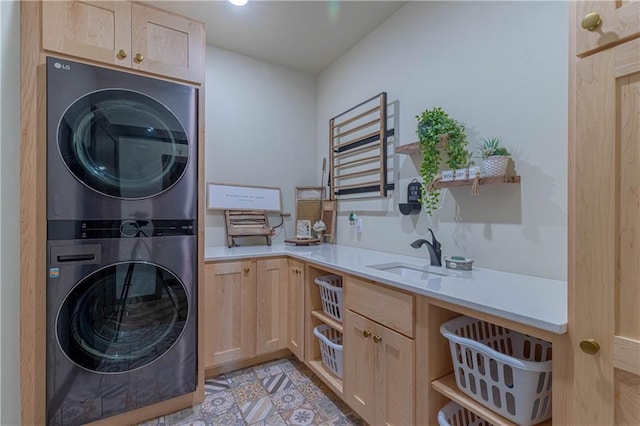 clothes washing area with stacked washer / drying machine, cabinets, and sink