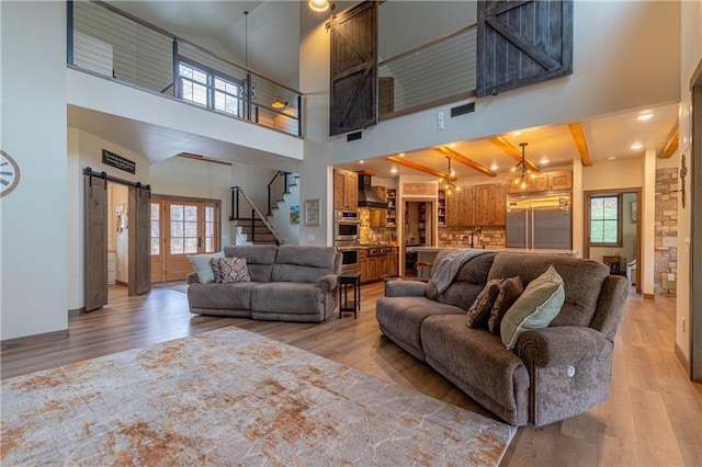 living room with a barn door, high vaulted ceiling, a healthy amount of sunlight, and hardwood / wood-style flooring