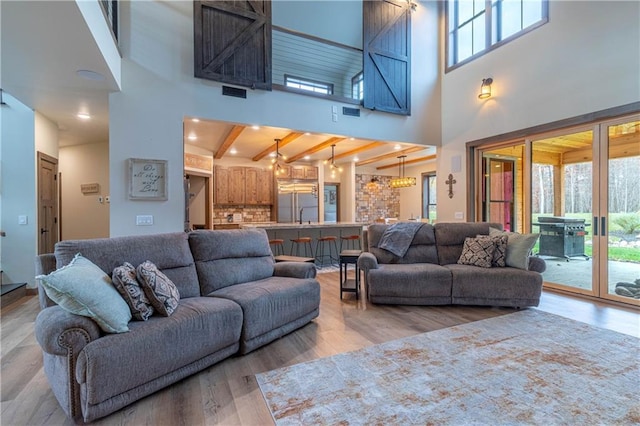 living room featuring beamed ceiling, a healthy amount of sunlight, hardwood / wood-style flooring, and a high ceiling