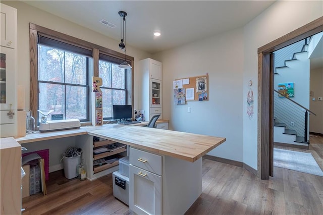 kitchen featuring wooden counters, white cabinets, decorative light fixtures, and light hardwood / wood-style floors