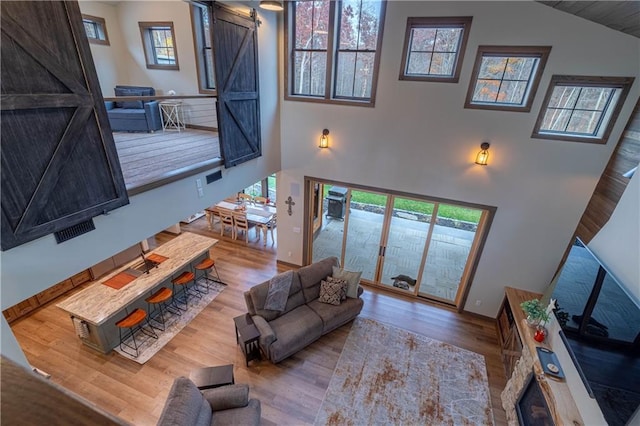 living room with high vaulted ceiling, light hardwood / wood-style flooring, and a barn door