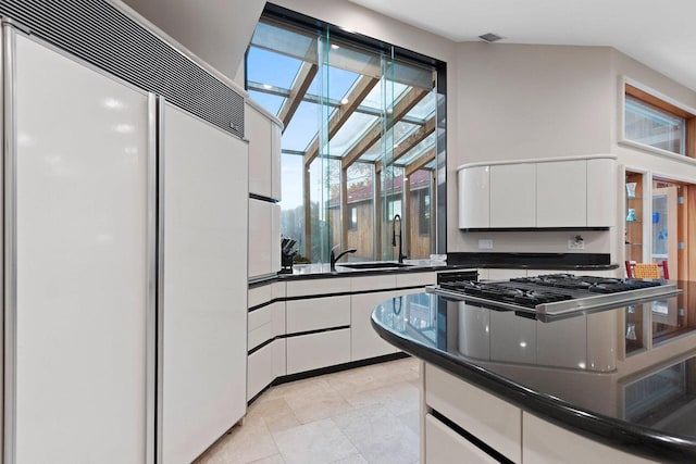 kitchen featuring white cabinetry, light tile patterned floors, sink, and paneled built in refrigerator