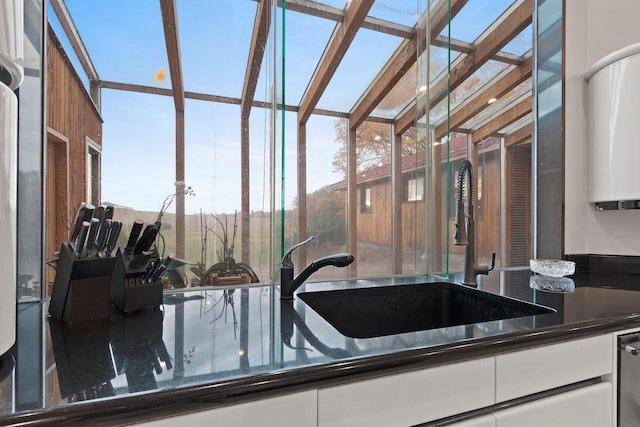 kitchen featuring white cabinets, dark stone countertops, and sink