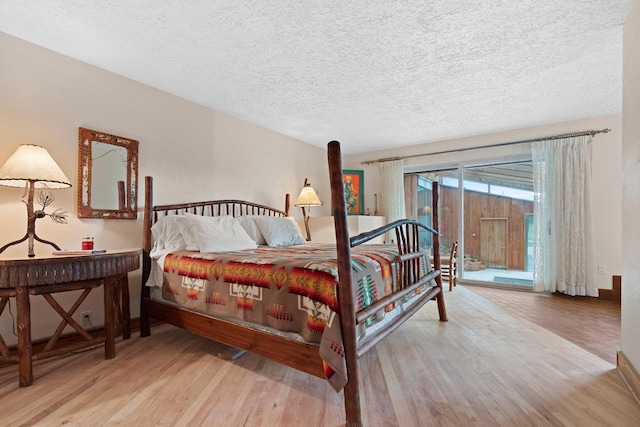 bedroom with light hardwood / wood-style floors, access to outside, and a textured ceiling