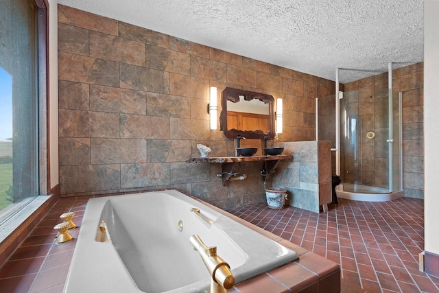 bathroom with tile walls, a textured ceiling, and separate shower and tub