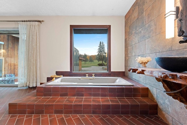 bathroom featuring a textured ceiling, tile walls, and tiled bath