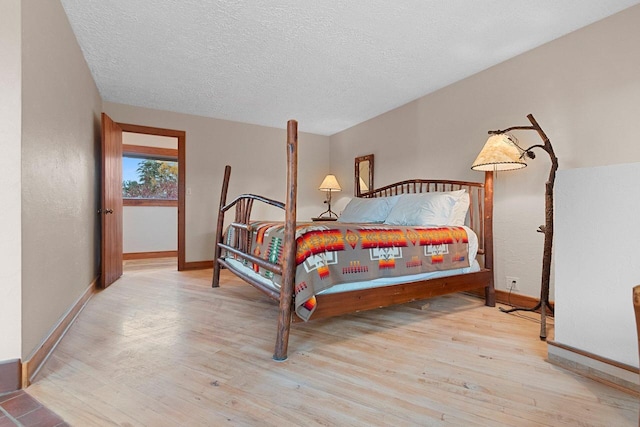 bedroom with a textured ceiling and light hardwood / wood-style flooring