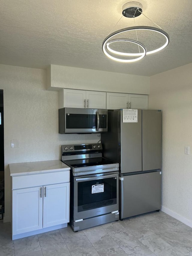 kitchen featuring appliances with stainless steel finishes, a textured ceiling, and white cabinets