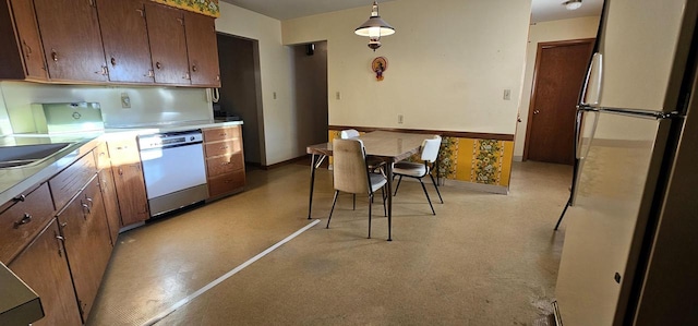 kitchen with sink, dishwasher, pendant lighting, and stainless steel refrigerator