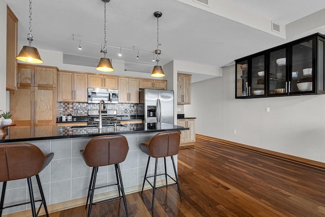 kitchen featuring a breakfast bar area, dark wood-type flooring, hanging light fixtures, backsplash, and appliances with stainless steel finishes