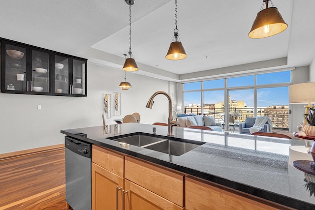 kitchen with hanging light fixtures, dark hardwood / wood-style flooring, dishwasher, dark stone countertops, and sink