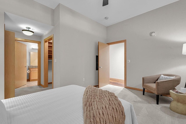 carpeted bedroom featuring a walk in closet, a closet, connected bathroom, and ceiling fan