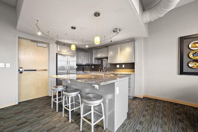 kitchen featuring tasteful backsplash, built in fridge, dark stone counters, pendant lighting, and gray cabinets