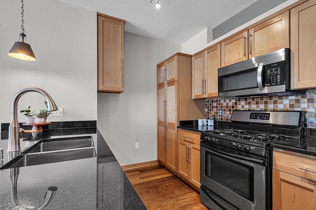 kitchen featuring dark stone countertops, stainless steel appliances, backsplash, and dark hardwood / wood-style flooring