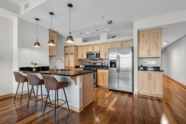 kitchen with light brown cabinetry, appliances with stainless steel finishes, sink, pendant lighting, and dark hardwood / wood-style floors