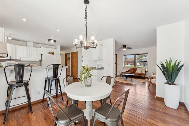 dining area with hardwood / wood-style flooring and ceiling fan with notable chandelier