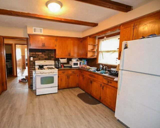 kitchen with beamed ceiling, sink, light wood-type flooring, and white appliances