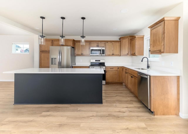 kitchen with stainless steel appliances, sink, hanging light fixtures, and a kitchen island