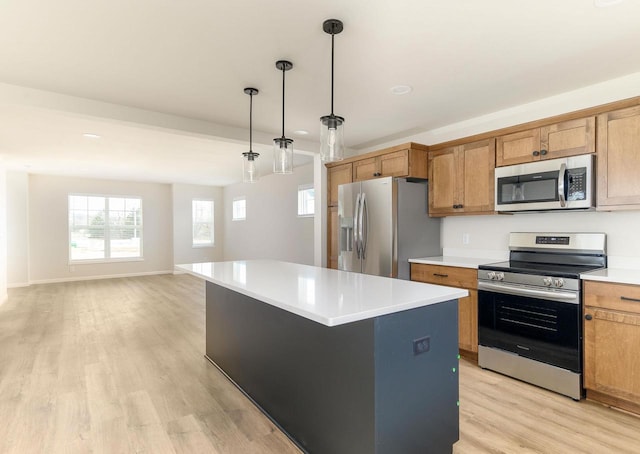 kitchen with stainless steel appliances, decorative light fixtures, a center island, and light hardwood / wood-style flooring