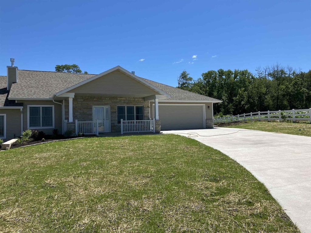 single story home with a porch, a front lawn, and a garage