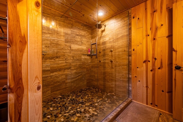 bathroom with a tile shower, wooden ceiling, and wood walls