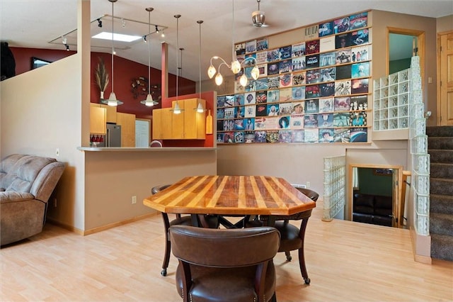 dining room featuring track lighting, lofted ceiling, and light wood-type flooring